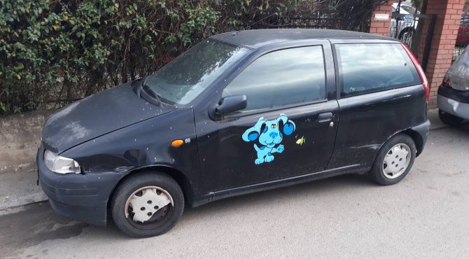 bočni prikaz crnog automobila Fiat Punto sa zalepljenim plavim stikerom na vratima